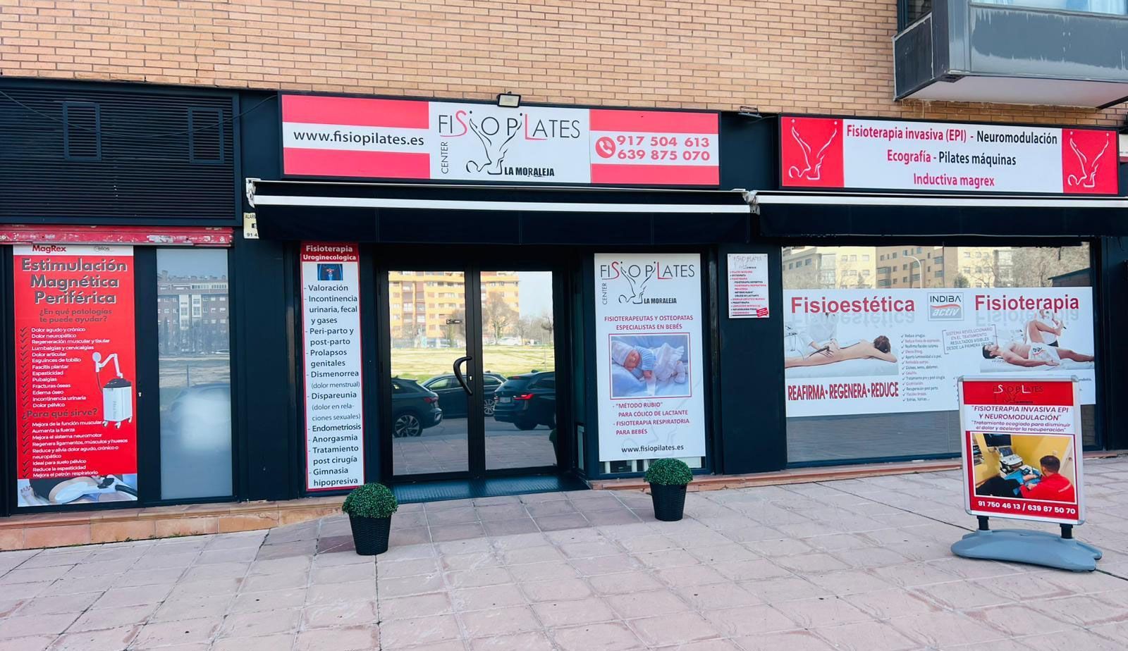 Escaparate de un centro de fisioterapia llamado "Fisioplates Madrid", con grandes ventanales en los que se exponen carteles y letreros sobre diversos tratamientos, como fisioterapia, estética y estimulación magnética.